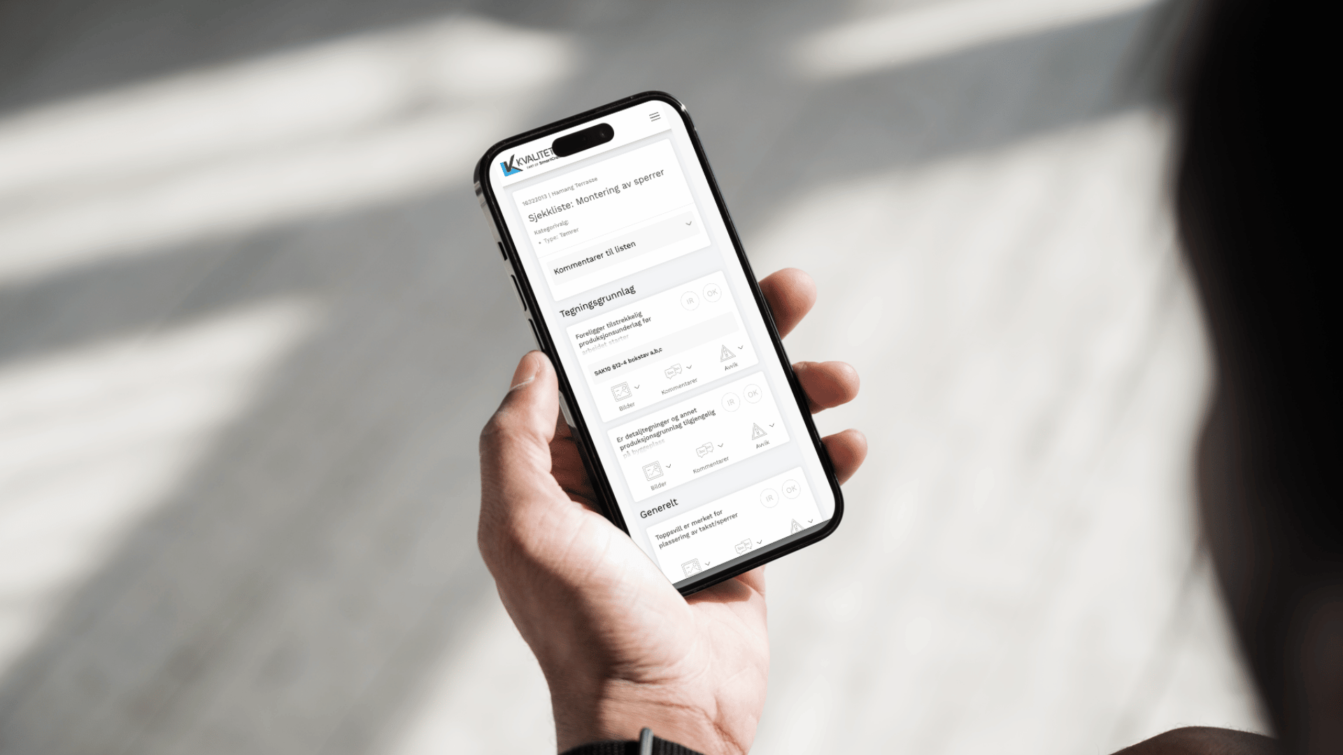 Hånd med telefon som viser sjekklister i Kvalitetskontroll